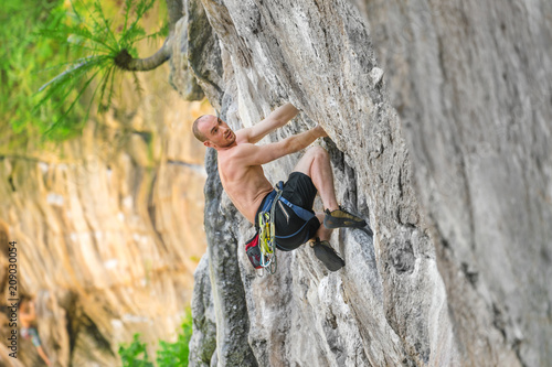 Young bald man climber climb a cliff without safety equipment