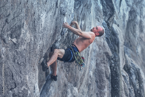 A man without safety equipment climbs the rock. Toned