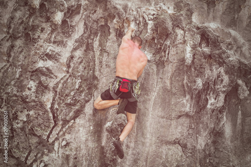 Fototapeta Naklejka Na Ścianę i Meble -  Young male climber climbing a rock wall. Toned