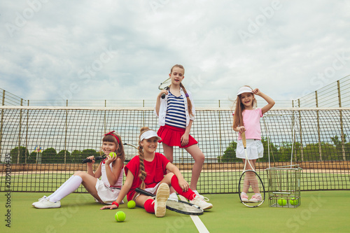 Fényképezés Portrait of group of girls as tennis players holding tennis racket against green