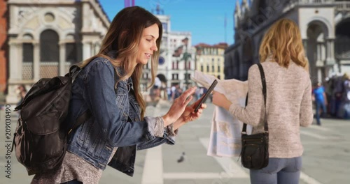 Beautiful brunette female tourist taking pictures with smart phone at St, Mark's Square, Attractive blonde woman looking at travel map in Venice, Italy while friend takes selfie, 4k