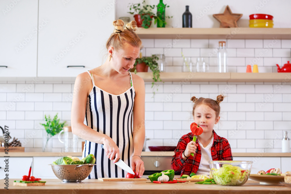 Picture of woman with her daughter cutting vegetables in kitchen Picture of woman with her daughter cutting vegetables in kitchen