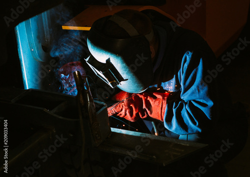 Man work with welding.Repairs the metal structure in the car.