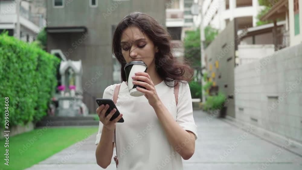 girl walking on city streets and drinking coffee to go in super slow motion girl walking on city streets and drinking coffee to go in super slow motion