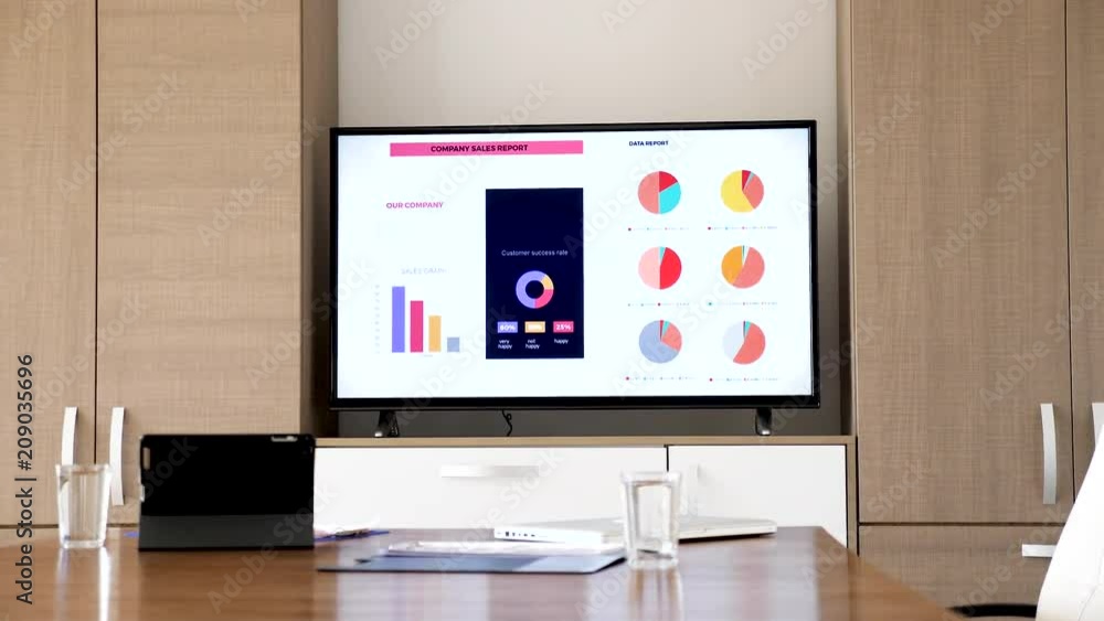 Business meeting conference empty room before the presentation. There is a TV ON that displays graphs and company sales report Business meeting conference empty room before the presentation. There is a TV ON that displays graphs and company sales report