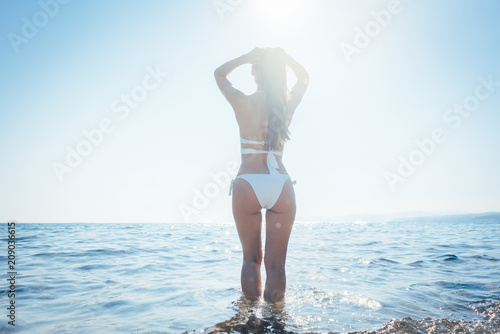Woman entering the sea in her summer vacation seen in backlight