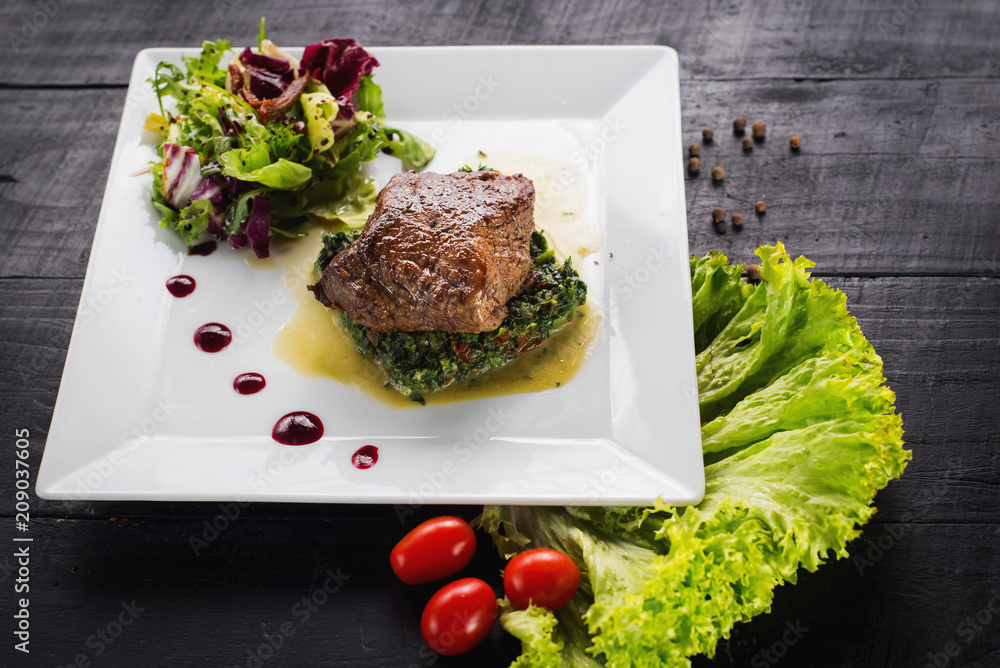 Fried piece of meat with herbs and spices on wooden background Fried piece of meat with herbs and spices on wooden background