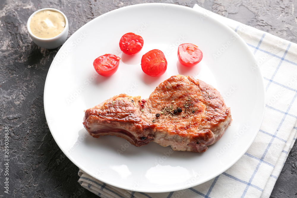 Plate with tasty grilled steak and tomatoes on table Plate with tasty grilled steak and tomatoes on table