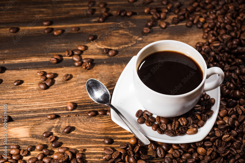 high angle view of coffee cup on rustic wooden table spilled with beans high angle view of coffee cup on rustic wooden table spilled with beans