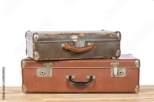 Old vintage suitcases on light wooden table isolated on a white background. Travel concept.