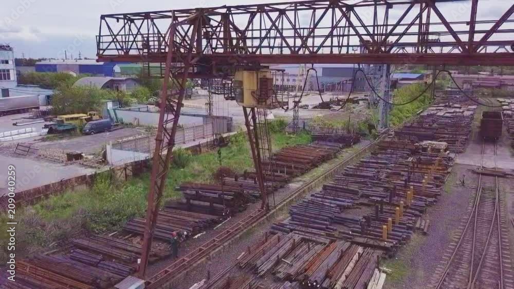 A gantry crane is moving over a metal warehouse. the camera monitors the cabin of the crane operator. Aerial video A gantry crane is moving over a metal warehouse. the camera monitors the cabin of the crane operator. Aerial video