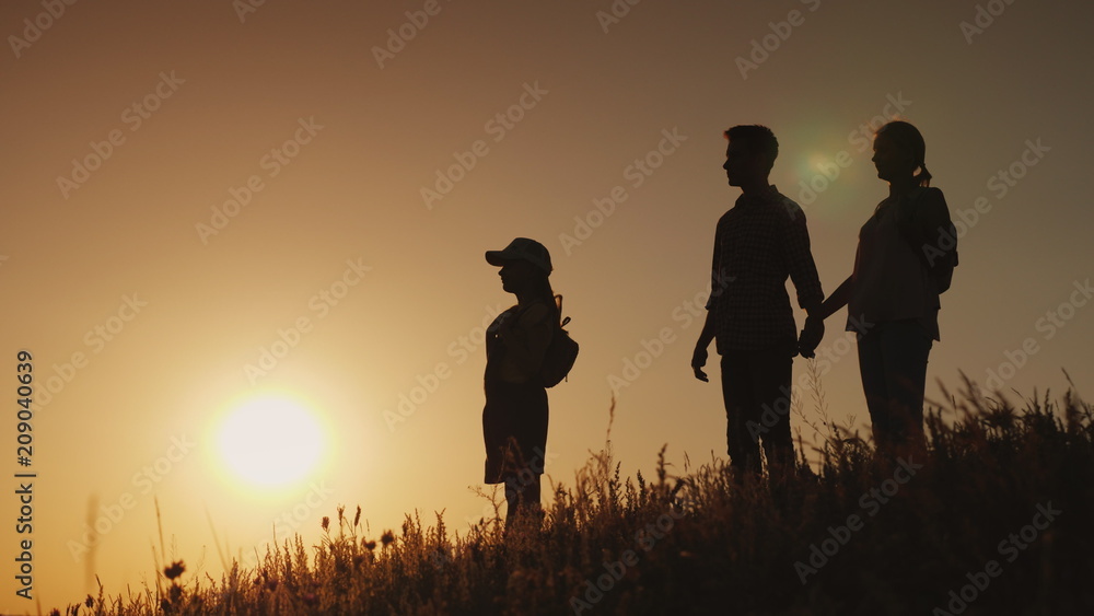 Silhouettes of a happy family, together they meet the dawn in a picturesque place