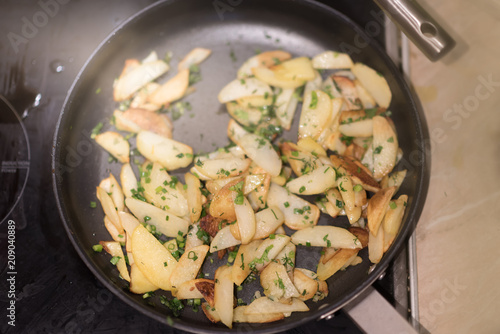 Fried potatoes with green onion on a metal pan