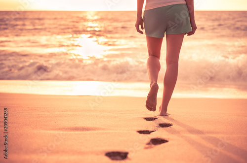 Woman walking on a beautiful tropical beach leaving foot prints in the sand.  © kieferpix
