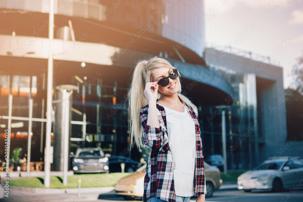 Fototapeta premium Beautiful blond young woman walking on the city street.