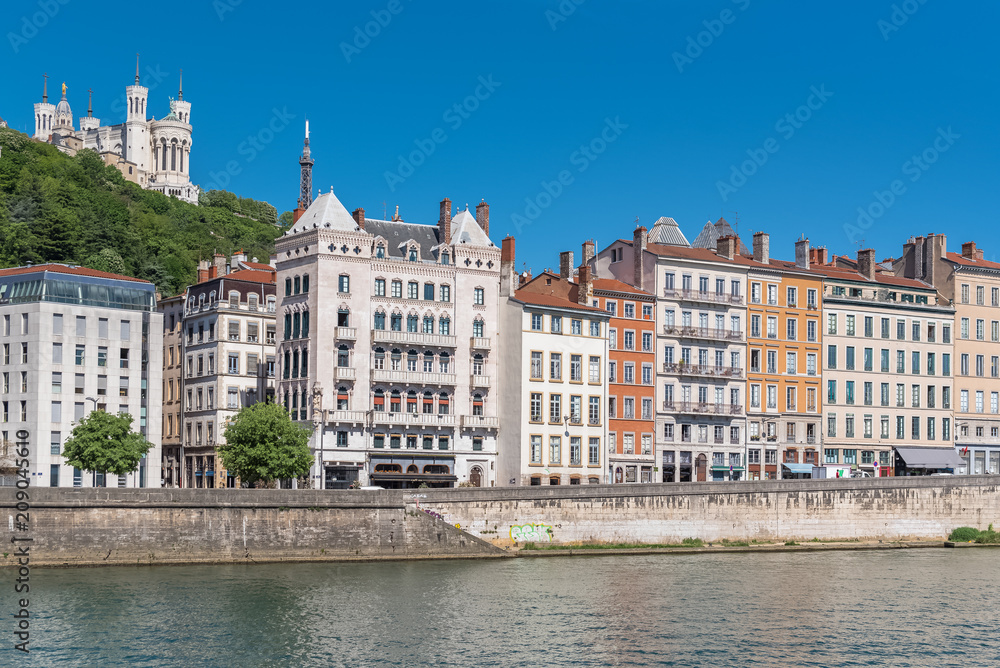 Vieux-Lyon, colorful houses in the center, on the river Saone, with the Fourviere cathedral in background 
