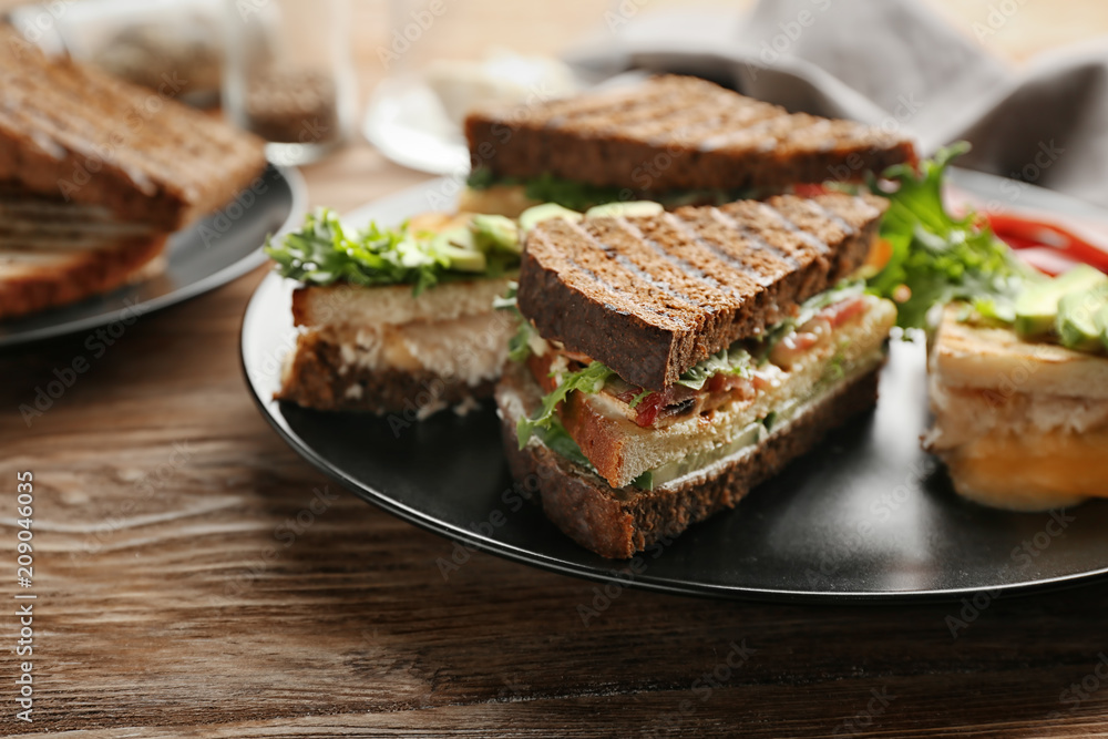 Plate with delicious sandwiches on wooden table Plate with delicious sandwiches on wooden table