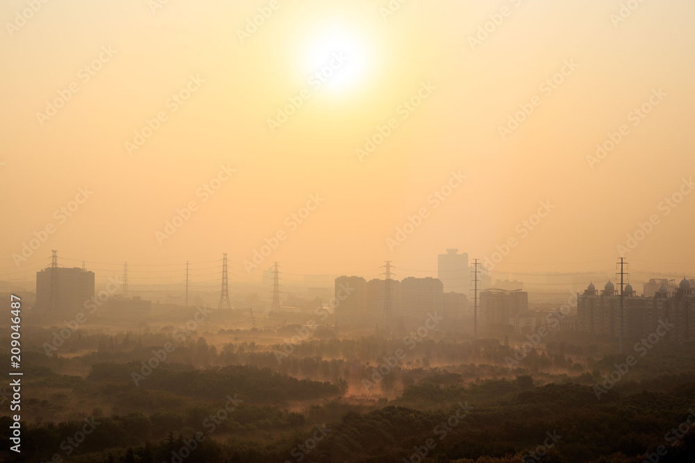 Bright sun rising over power lines and morning haze in a Shanghai suburb