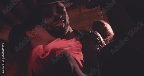 Woman in vampire costume biting man on neck on Halloween