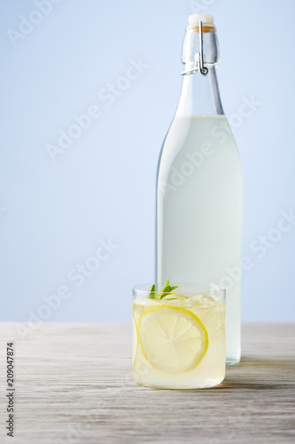 bottle and glass of fresh italian limoncello on wooden surface