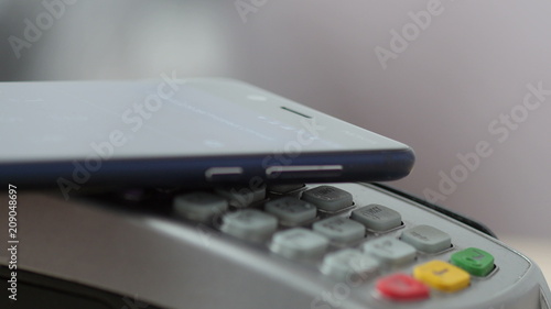 Customer paying with NFC technology by mobile phone on POS terminal. photo