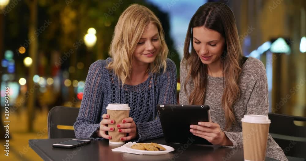 Lovely couple of girls sitting drinking and sharing tablet computer in Champs Elysees, Paris, France, Two attractive young women using portable tablet while drinking at table in European plaza, 4k Lovely couple of girls sitting drinking and sharing tablet computer in Champs Elysees, Paris, France, Two attractive young women using portable tablet while drinking at table in European plaza, 4k