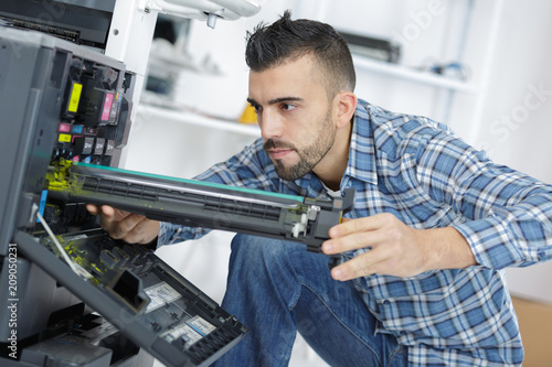 young male technician repairing digital photocopier machine