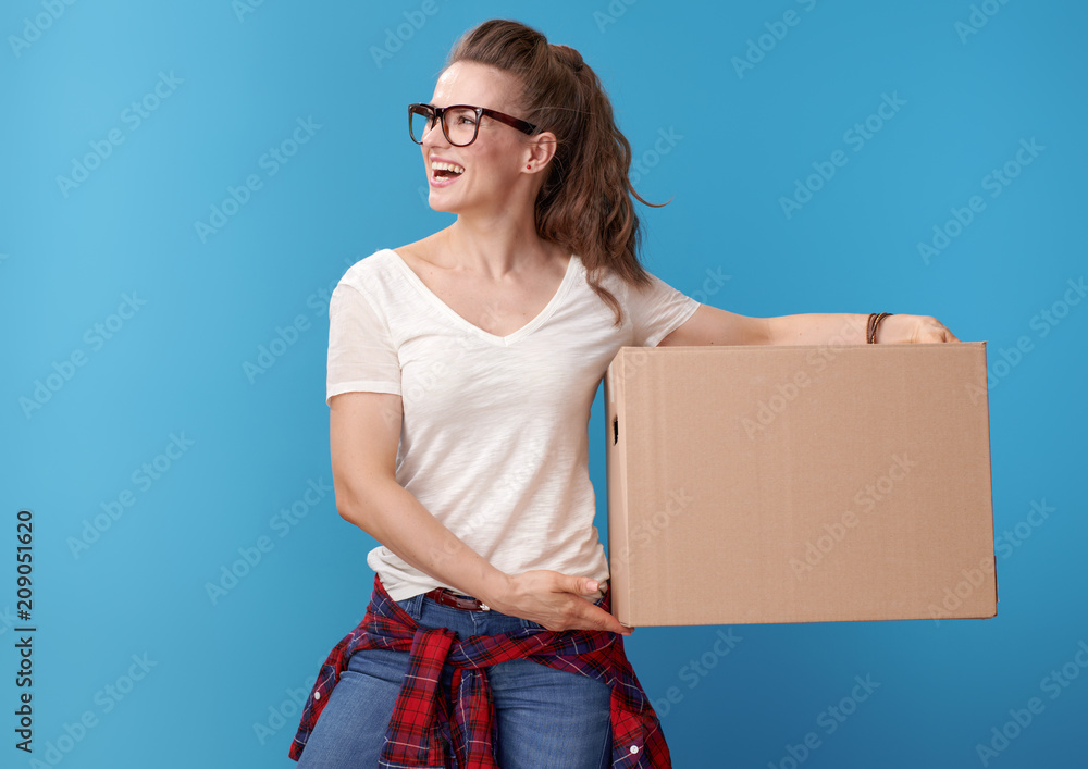 happy woman with cardboard box looking at copy space on blue happy woman with cardboard box looking at copy space on blue