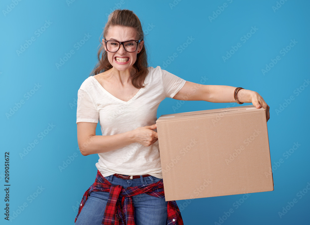 furious young woman in white shirt with cardboard box on blue furious young woman in white shirt with cardboard box on blue