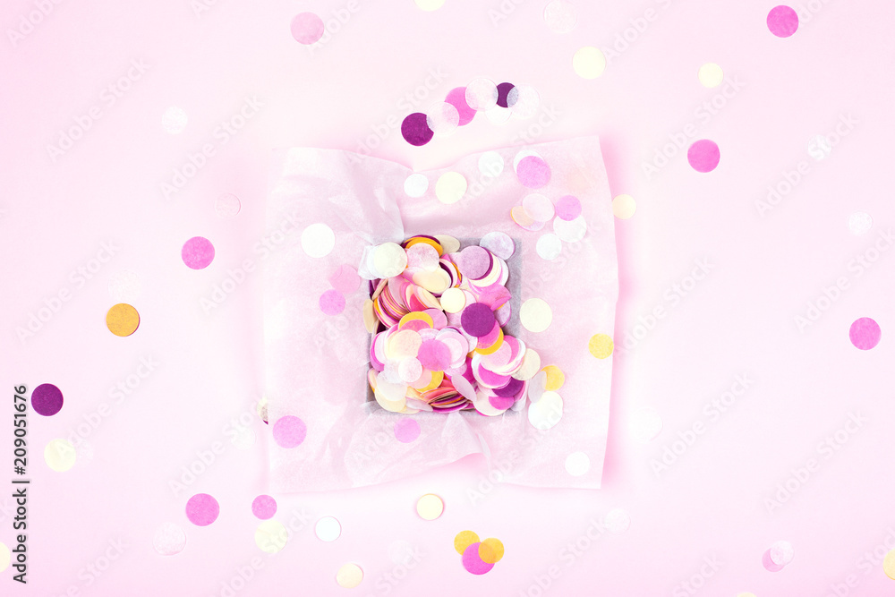 One box with colorful confetti on pink background. Festive card. Top view.