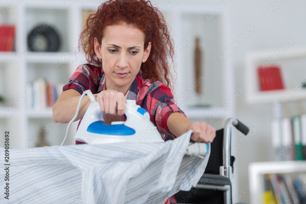 pretty redhead woman sitting on wheelchair and ironing pretty redhead woman sitting on wheelchair and ironing