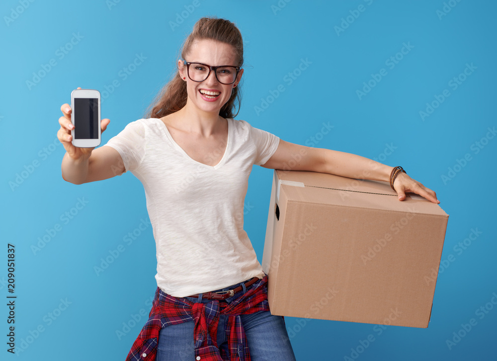 woman with cardboard box showing cellphone blank screen on blue woman with cardboard box showing cellphone blank screen on blue