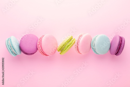 The row of colorful macarons on pink background. Top view.