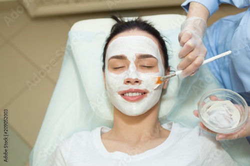 beautiful young girl on a facial treatment in a beauty salon applying a cream