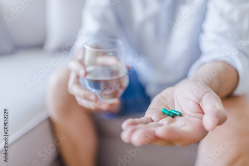 age  medicine  healthcare and people concept - close up of senior man hands with pills and water glass at home