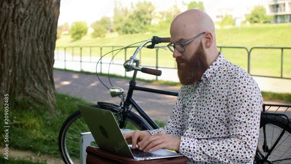 Hipster businessman using a laptop outdoors Hipster businessman using a laptop outdoors