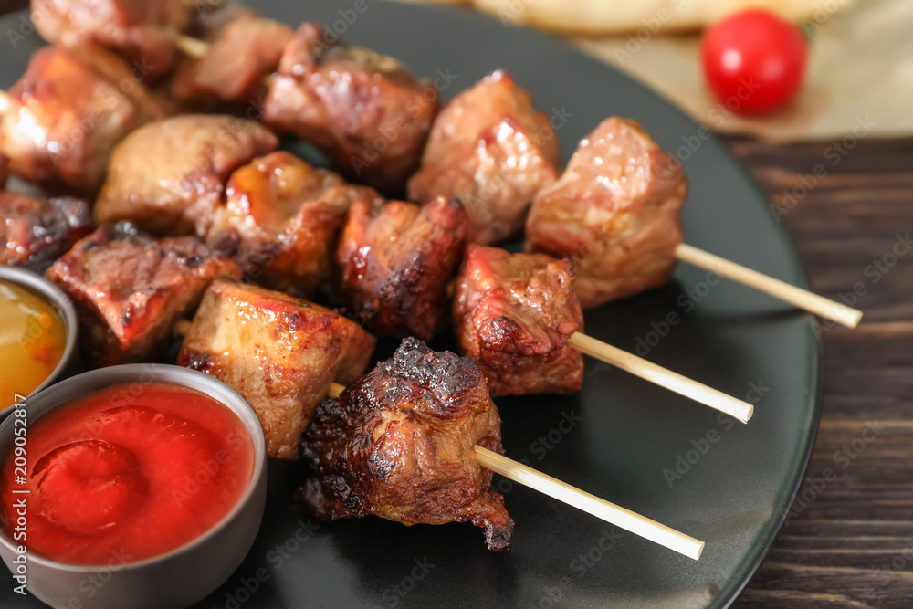 Barbecue skewers with juicy meat and sauces on plate
