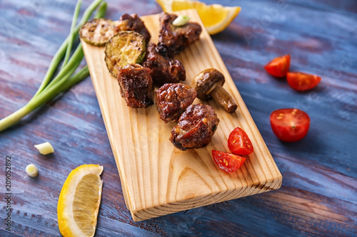 Pieces of shish-kebab with vegetables on wooden board