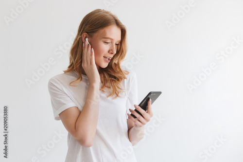 Happy young redhead woman listening music with earphones by mobile phone. © Drobot Dean