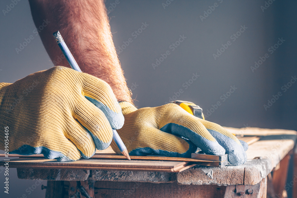 Obraz premium The worker places a mark and draws a cutting line on the laminate mounting board