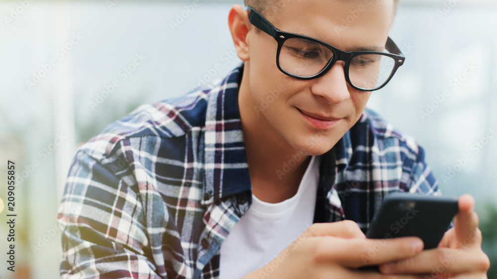 Man in the glasses using smart phone in the city. Man in the glasses using smart phone in the city.