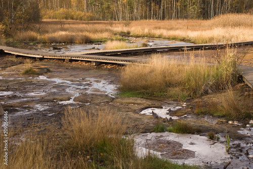 Low wooden trail over drying water stream.