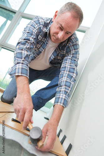 Man using rubber mallet to position laminate flooring