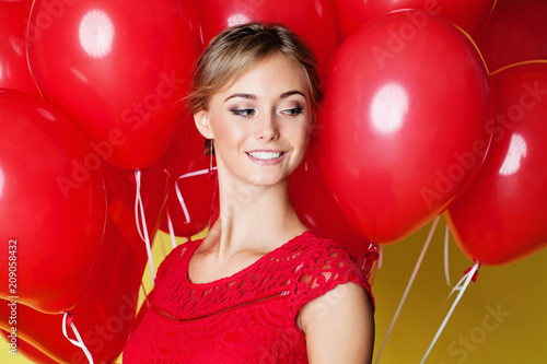 Beautiful young woman face on yellow background with balloons, closeup portrait © artmim