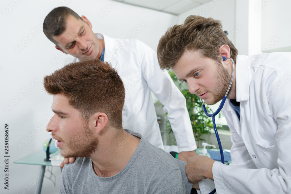 Obraz premium young internist healing patient under experienced doctors surveillance