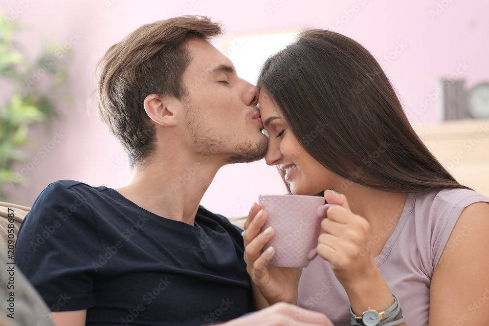 Happy young couple drinking hot coffee while resting at home Happy young couple drinking hot coffee while resting at home