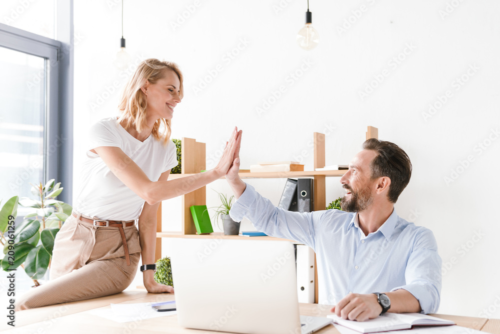 Couple of excited colleagues giving high five