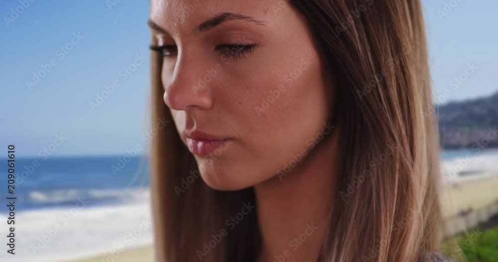 Close-up portrait of pretty brunette deep in thought in serene beach setting, Close-up of millennial girl in her 20s looking pensive outside while at the beach, 4k