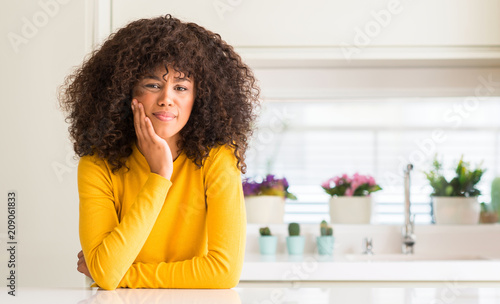 African american woman wearing yellow sweater at kitchen touching mouth with hand with painful expression because of toothache or dental illness on teeth. Dentist concept.