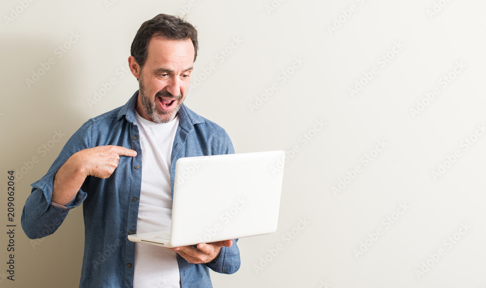 Senior man using laptop computer with surprise face pointing finger to himself Senior man using laptop computer with surprise face pointing finger to himself